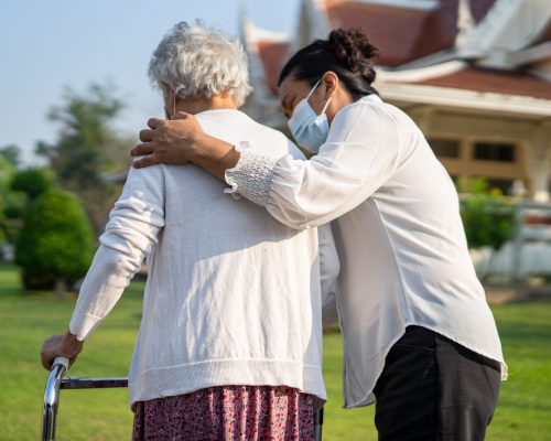 Caregiver help and care Asian senior or elderly old lady woman use walker with strong health while walking at park in happy fresh holiday.